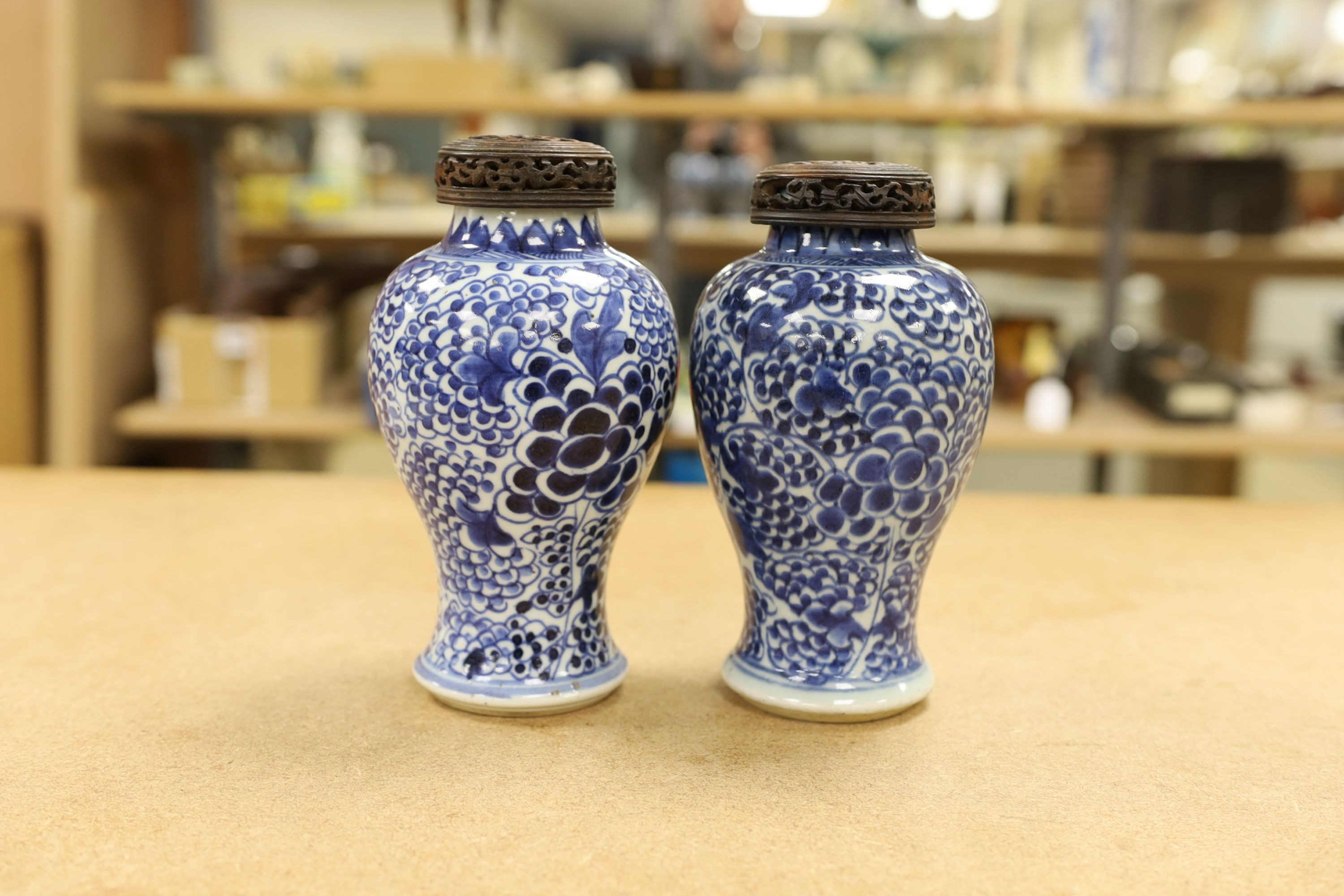 A pair of Chinese blue and white 'phoenix' vases, Kangxi, associated wood covers, 19cm including covers